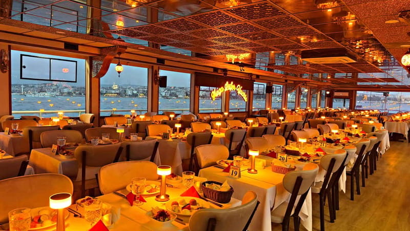 Tables laid under warm lights in the dining saloon of a Bosphorus cruise boat